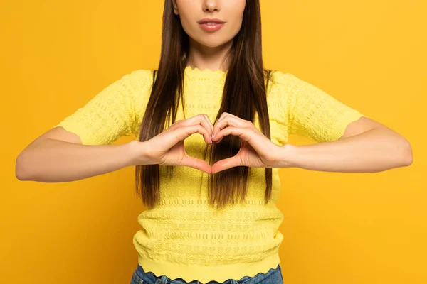 Vista recortada de la mujer mostrando signo de amor sobre fondo amarillo - foto de stock