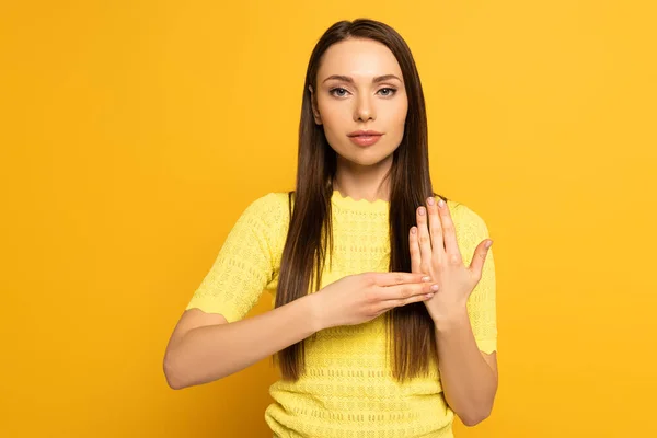 Muchacha atractiva usando lenguaje de señas sobre fondo amarillo - foto de stock