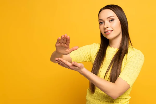 Smiling girl using deaf and dumb language on yellow background — Stock Photo