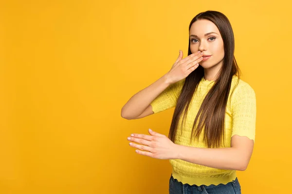 Donna che mostra gesto da linguaggio sordo e muto su sfondo giallo — Foto stock