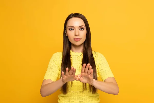 Belle femme montrant signe dans un langage sourd et muet sur fond jaune — Photo de stock