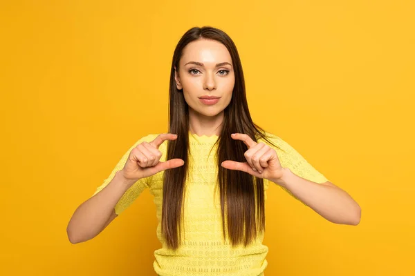 Woman looking at camera while showing gesture from sign language on yellow background — Stock Photo