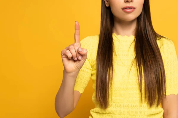 Ausgeschnittene Ansicht einer jungen Frau, die mit dem Finger auf gelbem Hintergrund zeigt — Stockfoto