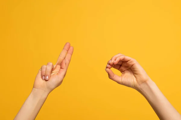 Cropped view of woman showing letters from deaf and dumb language on yellow background — Stockfoto