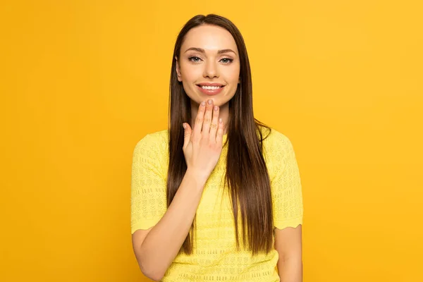 Smiling woman showing word speak in deaf and dumb language on yellow background — Stock Photo