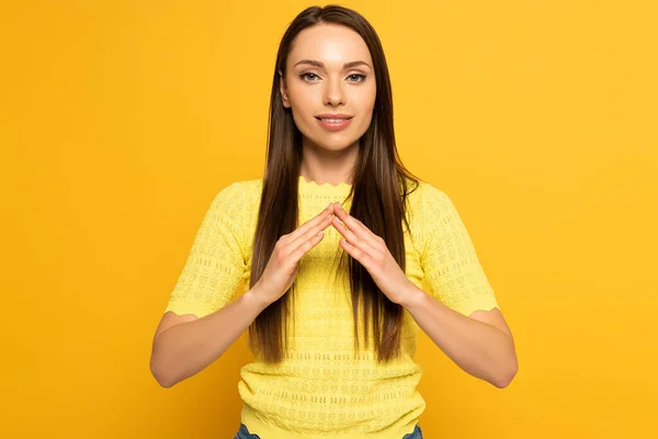 Smiling girl showing home gesture in deaf and dumb language on yellow background — Stock Photo