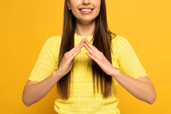 Vue recadrée d'une femme souriante montrant un geste à la maison dans un langage sourd et muet sur fond jaune — Photo de stock