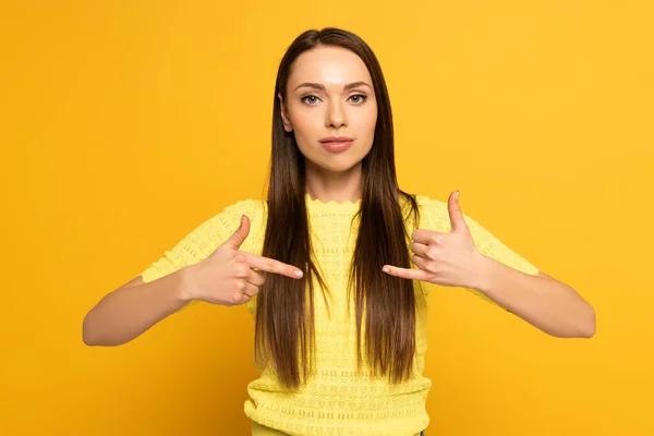 Привлекательная девушка жестикулирует при использовании языка жестов на желтом фоне — стоковое фото