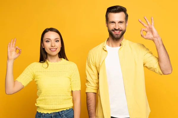 Jeune couple souriant montrant un geste correct sur fond jaune — Photo de stock