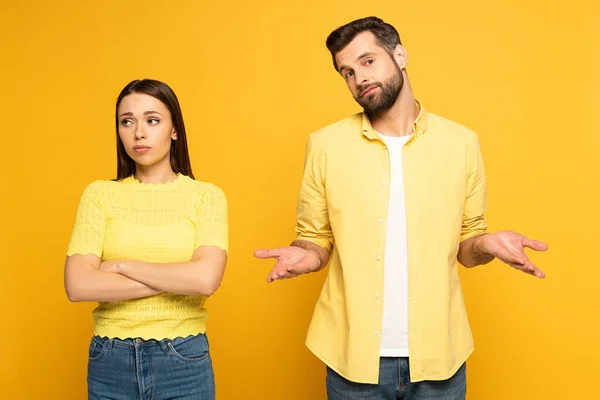 Confused man standing near spherical girlfriend on yellow background — Stock Photo