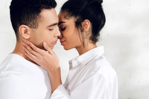 Donna afroamericana con gli occhi chiusi baciare uomo su sfondo bianco — Foto stock