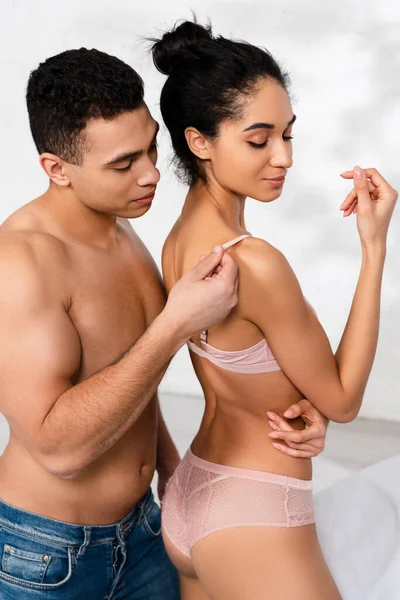 Homme derrière la femme afro-américaine toucher soutien-gorge sangle dans la chambre — Photo de stock