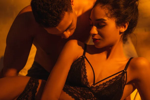 Мужчина целует сексуальную африканскую американку в спальне — стоковое фото