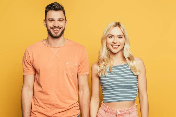 Glücklicher schöner Mann und attraktives blondes Mädchen lächeln in die Kamera isoliert auf gelb — Stockfoto