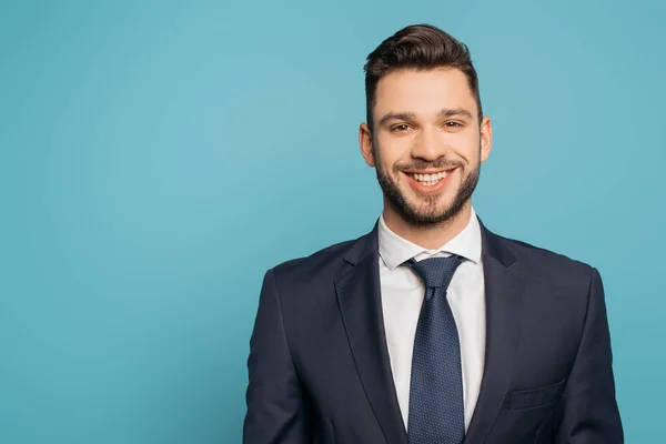 Alegre, guapo hombre de negocios sonriendo a la cámara aislado en azul - foto de stock