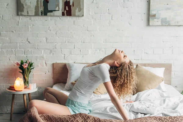 Attraktives Mädchen auf dem Bett im gemütlichen Schlafzimmer mit Himalaya-Salzlampe — Stockfoto