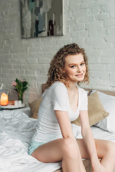 Улыбающаяся девушка в уютной спальне с гималайской соляной лампой — стоковое фото