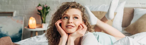 Dreamy girl lying on bed in bedroom with Himalayan salt lamp, panoramic concept — Stock Photo