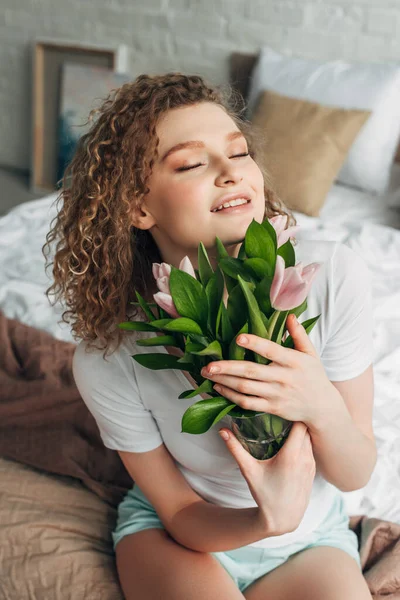 Glückliches attraktives Mädchen in Homewear mit Tulpenblumen am Morgen — Stockfoto