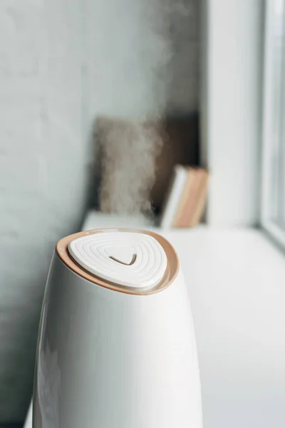 Humidificateur répandant la vapeur et debout sur le rebord de la fenêtre à la maison — Photo de stock