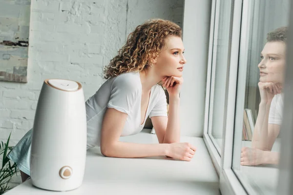 Beautiful girl with ultrasonic air purifier on windowsill — Stock Photo