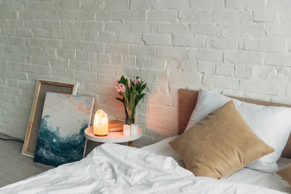 Interno della camera da letto con lampada al sale himalayano, fiori e candele — Foto stock