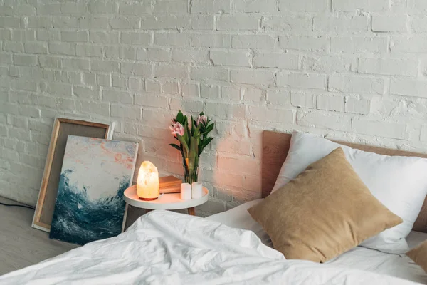 Interior del dormitorio con lámpara de sal del Himalaya, flores y velas - foto de stock