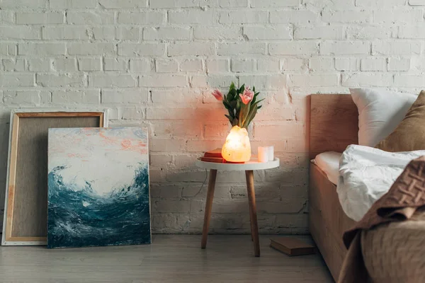 Interior of bedroom with Himalayan salt lamp, flowers, paintings and candles — Stock Photo