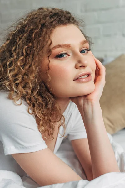 Positive attractive curly girl in homewear on bed in morning — Stock Photo