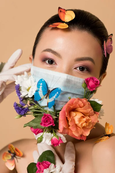 Attractive asian woman in latex gloves and floral face mask with butterflies isolated on beige — Stock Photo