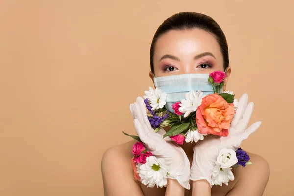 Beautiful nude asian girl in latex gloves and floral face mask isolated on beige — Stock Photo