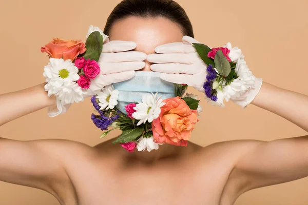 Chica desnuda en guantes de látex y mascarilla floral cerrando ojos aislados en beige - foto de stock