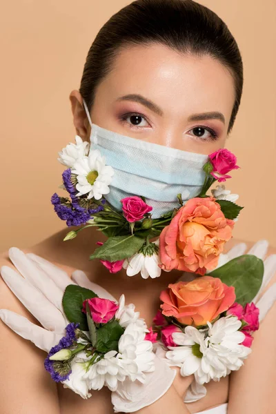 Atractiva chica asiática desnuda en guantes de látex y mascarilla floral aislada en beige - foto de stock