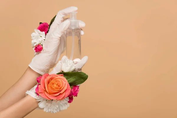 Ausgeschnittene Ansicht einer Frau in floralen Latex-Handschuhen mit antiseptischem Spray isoliert auf beige — Stockfoto