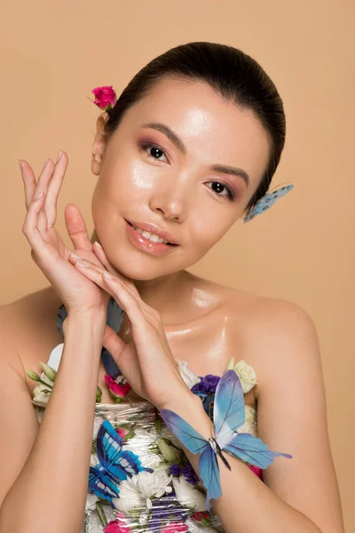 Atractivo tierno desnudo asiático chica en flores con mariposas en cuerpo aislado en beige - foto de stock
