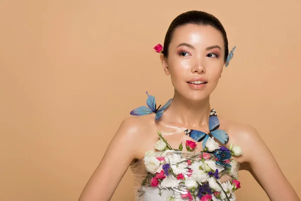 Hermosa tierna chica asiática desnuda en flores con mariposas en el cuerpo aislado en beige - foto de stock