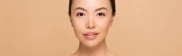 Панорамний знімок привабливої азіатської дівчини з оголеним макіяжем ізольовано на бежевому — стокове фото