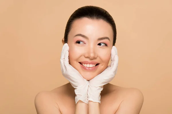 Belle sourire nu asiatique fille en latex gants isolé sur beige — Photo de stock