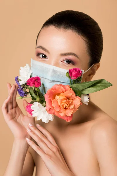 Привлекательная обнаженная азиатка в цветочной маске, изолированная на бежевом — стоковое фото