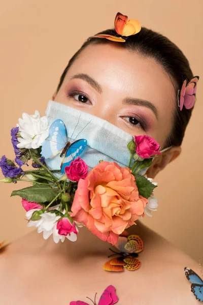 Приваблива азіатська жінка в латексних рукавичках і квітковій масці для обличчя з метеликами на бежевому — стокове фото