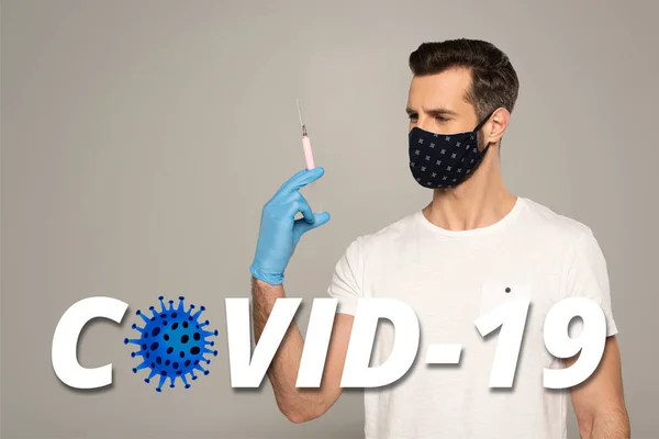 Man in safety mask and latex glove holding syringe isolated on grey, covid-19 illustration — Stock Photo