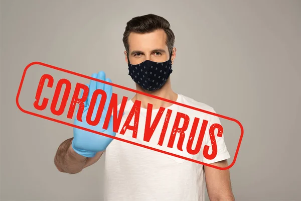 Hombre con máscara de seguridad y guante de látex mostrando gesto de stop aislado en gris, ilustración coronavirus - foto de stock
