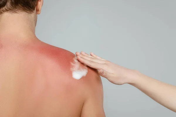 Vue recadrée de la femme appliquant de la mousse sur la peau masculine isolée sur gris — Photo de stock