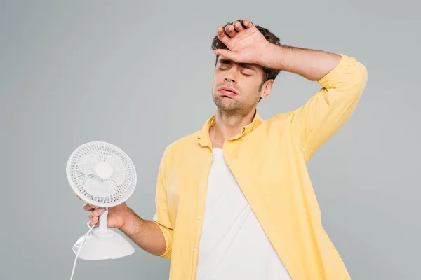 Чоловік з настільним вентилятором, який страждає від тепла ізольовано на сірому — стокове фото