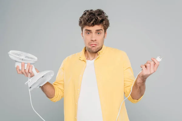 Vue de face de l'homme confus avec ventilateur de bureau regardant la caméra isolée sur gris — Photo de stock