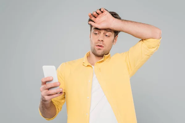 Front view of man with raised hand looking at smartphone isolated on grey — Stock Photo