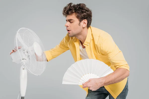 Homem desfrutando de ventiladores elétricos e manuais com olhos fechados isolados em cinza — Fotografia de Stock