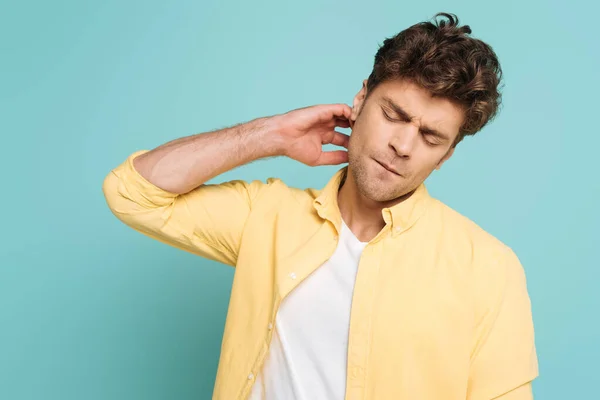 Mann mit geschlossenen Augen kratzt Hals isoliert auf blau — Stockfoto