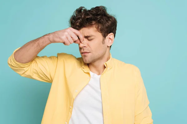 Man with closed eyes suffering from runny nose isolated on blue — Stock Photo