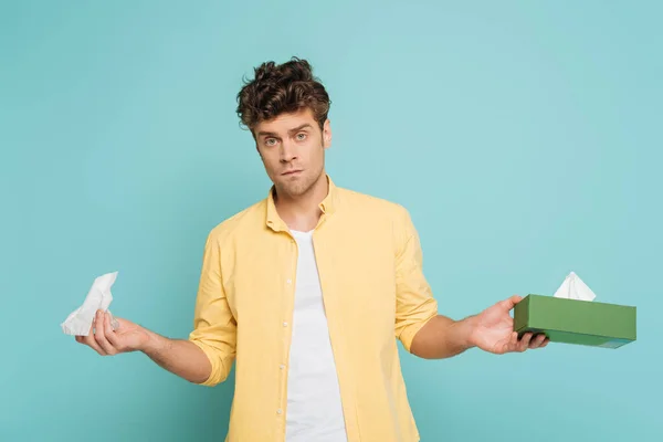Front view of man looking at camera and holding box with napkins isolated on blue — Stock Photo